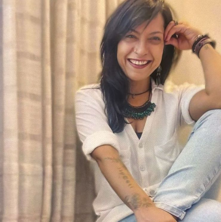 Retrato de Regina Fonseca, professora de yoga e psicóloga clínica, em pose relaxada e sorridente.